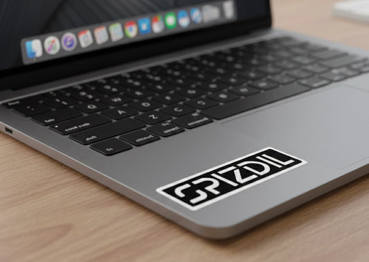 SPIZDIL™ Asset Tag Signature Logo Signet Sticker on a space gray Apple MacBook Pro lid — Industrial aesthetic tech decal.